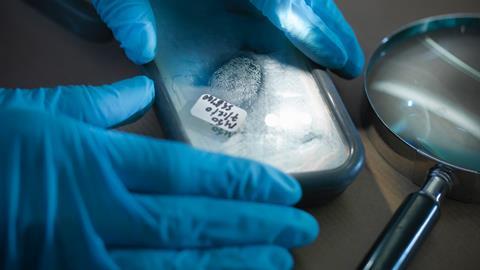 An image showing a close up of forensic scientist examining finger print in laboratory