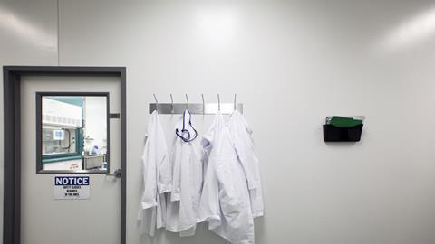 Closed door to laboratory with lab coats hanging from coat rack