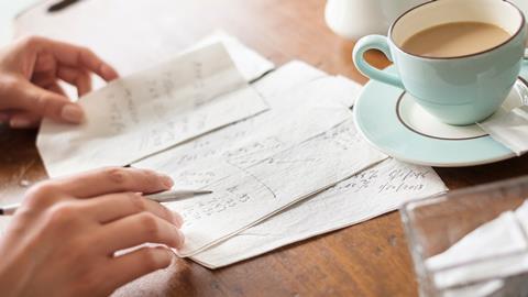 Someone having a cup of tea while doing calculations on a napkin