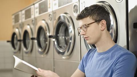 A photograph of a young man reading book in laundry