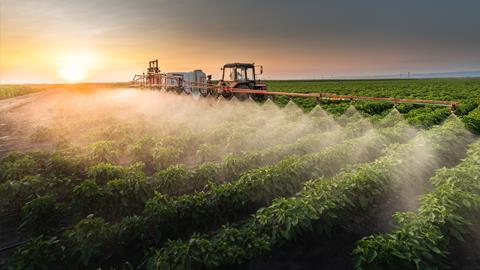 Tractor spraying glyphosate at sunset