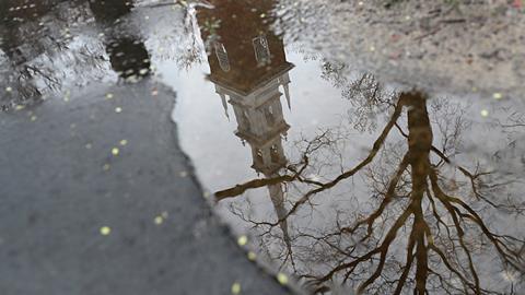 An image showing how the Memorial Church in Harvard Yard is reflected in a puddle on an empty campus at Harvard University