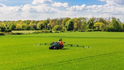 tractor spraying glyphosate pesticides on a field