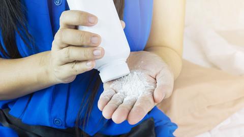 Image showing woman sitting down pouring talcum powder out of a bottle and into her hand