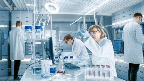Researchers in a lab, observing blue liquid in a beaker