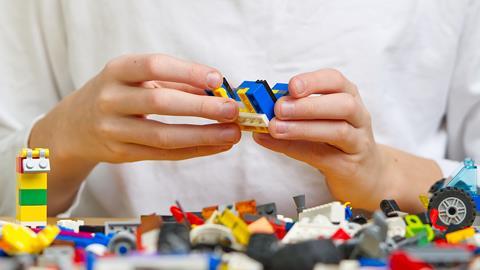 Close up of hands playing with colorful plastic bricks at a table