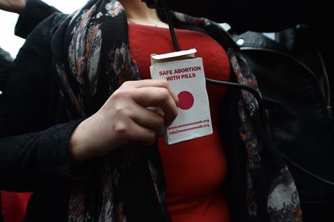 An image showing the hands of a woman holding a packet that reads 