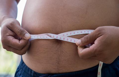 A man measuring his waistline with a measuring tape