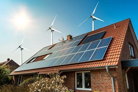 A photograph showing solar panels on a house and wind turbines