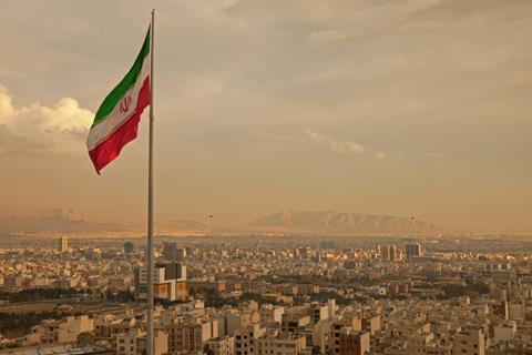 The Iranian flag flying above the Tehran skyline.