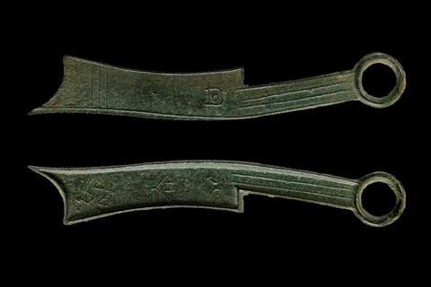 A pair of objects that look like stylised knives, and are about the same size. Their heavy patina suggests they are made from bronze.