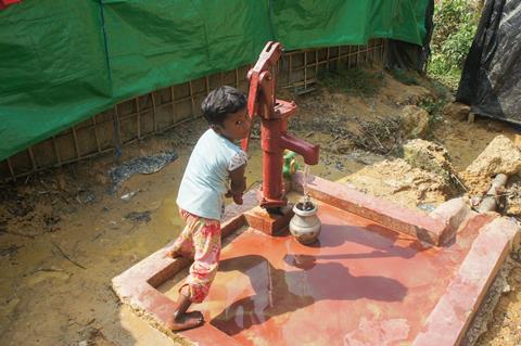 An image showing a small girl collecting water from tube well in Bangladesh