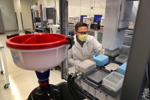 An image showing a clinical lab technician using robots in the lab