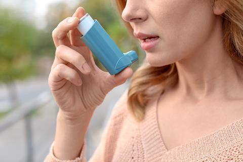 An image showing a woman using an inhaler