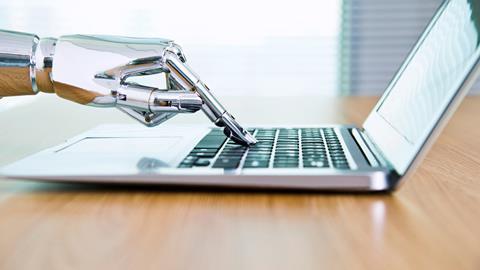 An image showing a robot's hand typing on a laptop
