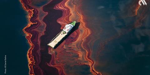 A ship drifts through a heavy band of oil, spilled from Deepwater Horizon wellhead in the Gulf of Mexico, May 2010