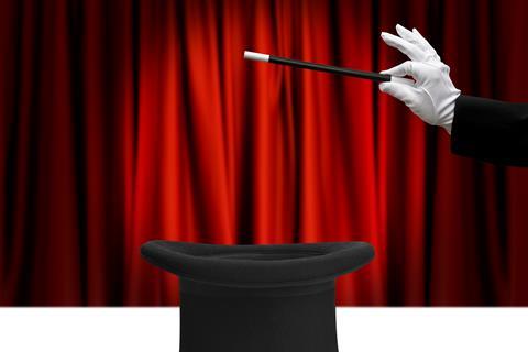 An image showing a magician's hand hovering a wand on top of a top hat