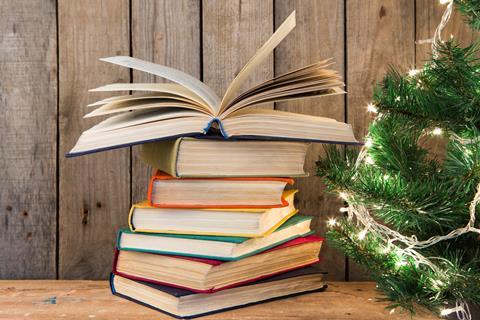 A pile of books by a Christmas tree