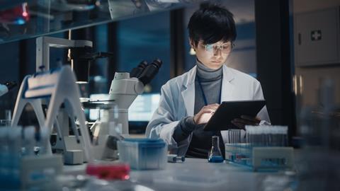 A scientist uses a tablet at a desk in a laboratory
