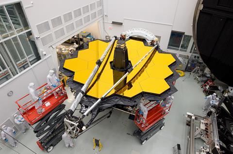 An image showing workers next to the James Webb Space Telescope