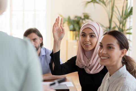 A woman in a meeting raising her hand