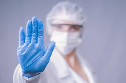 Researcher wearing lab PPE including gloves, eye protection and mask