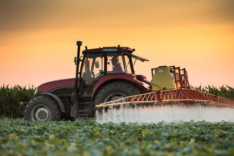 Tractor spraying pesticides on vegetable field