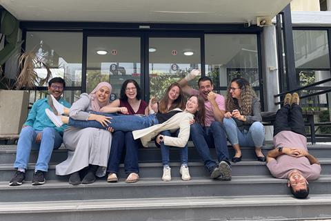 A diverse group of happy laughing young people sitting and joking on the steps of a University