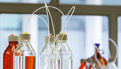 A close up photograph of clear and amber bottles with plastic hose for high performance liquid chromatography