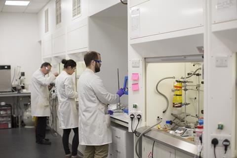 An image showing chemists working in fumehoods inside the labs of Unit DX 
