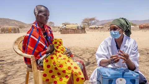 Image showing a woman in traditional African attire with a doctor about to inject a vaccine