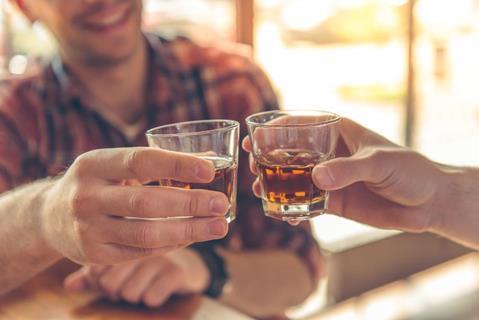 An image of people clinking whiskey glasses