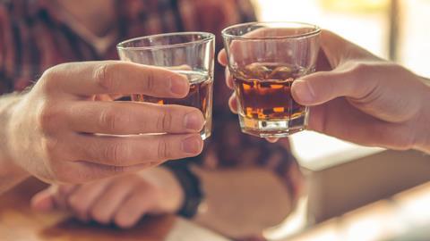 An image of two men clinking whiskey glasses