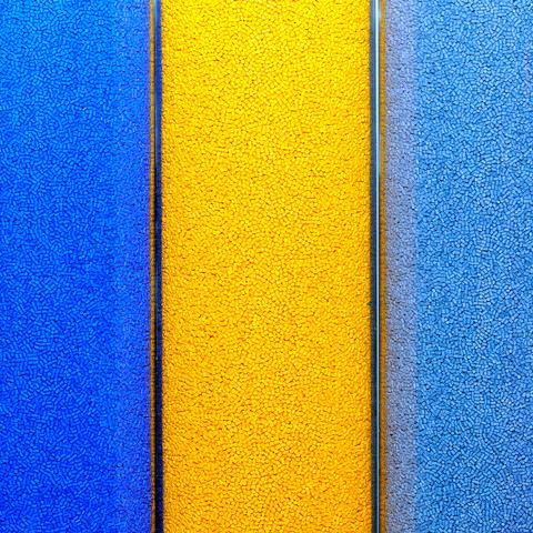An image showing green, blue, yellow and red plastic pellets in trays