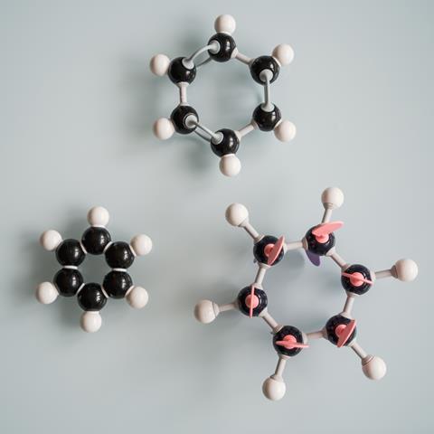 Three benzene ball and stick models arranged on a grey background
