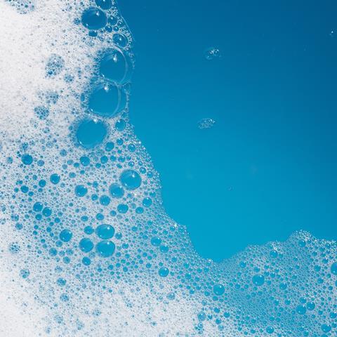 Detergent foam bubble on water with blue background.
