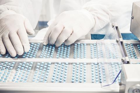 image shows medicines and the gloved hands of a lab worker