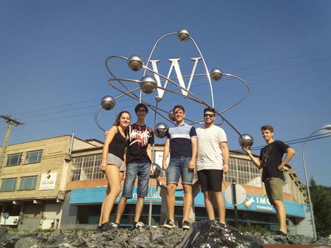 An image showing a group of students in front of a sculpture representing a tungsten atom