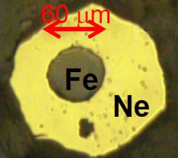 A rough yellow circle labelled Ne surrounding a grey circle labelled Fe and marked as 60 microns across