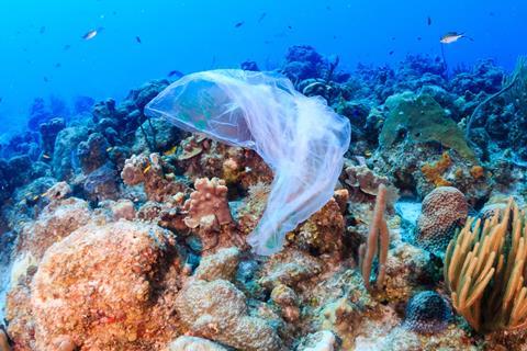 Plastic pollution: a discarded plastic rubbish bags floats on a tropical coral reef presenting a hazard to marine life