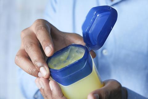 A photo of someone holding a jar of petroleum jelly