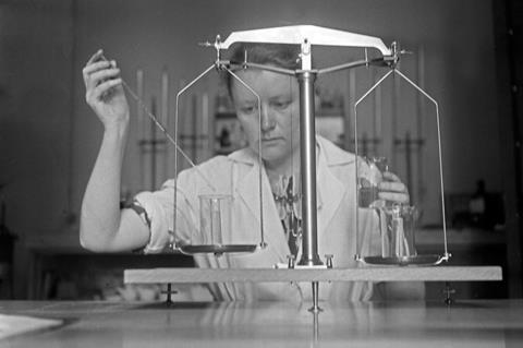 Researcher using a 1930s beam-type balance for analytical work