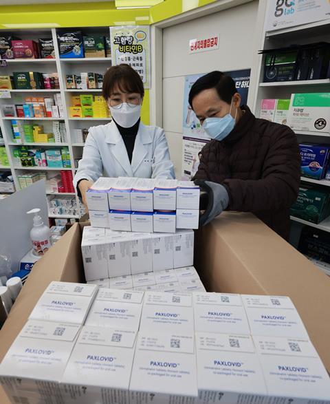 An image showing two pharmacists with Paxlovid boxes