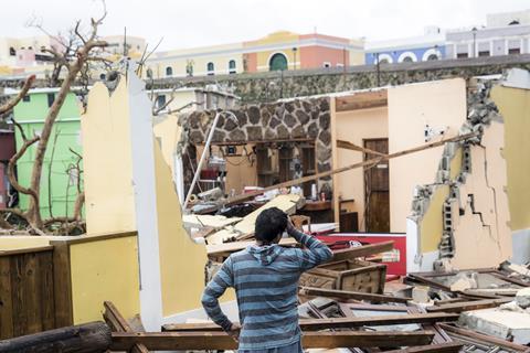 An image showing a puzzled man looking at the damaged that the Hurricane Maria in Puerto Rico had done to a house