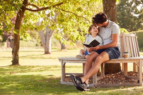 Father sitting on a bench with child reading a book