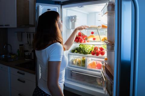 Woman looking at food inside of a fridge 