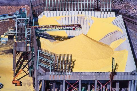 Industrial conveyor belts carrying a yellow sulphurous powder onto a large pile