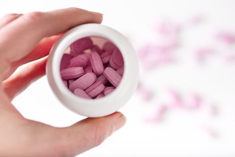 Hand holding jar of pink pills 