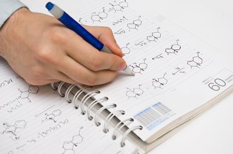 Hand writing organic chemistry structures in ballpoint pen on a notebook