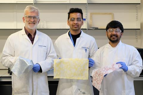 Photo of thee scientists in the lab holding fabric swatches